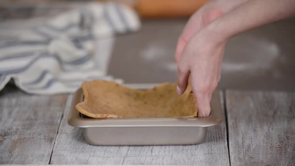El proceso de hacer una base para un pastel de corteza corta, manos femeninas transferir una hoja de masa enrollada en un plato para hornear. — Vídeo de stock