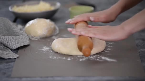 As mãos femininas cozinham rolar a massa para o rolo de khachapuri em uma mesa de madeira, polvilhada com farinha. — Vídeo de Stock