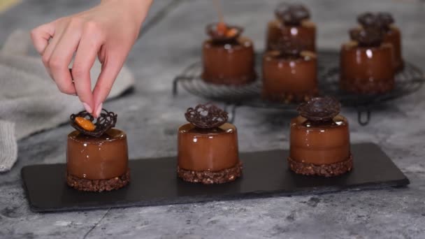 Chef pâtissier décorer un dessert mousse au chocolat avec caramel amande. Gâteau européen moderne. — Video