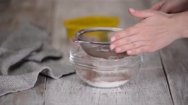Kadın elleri un ve kakao tozu süzüyor.