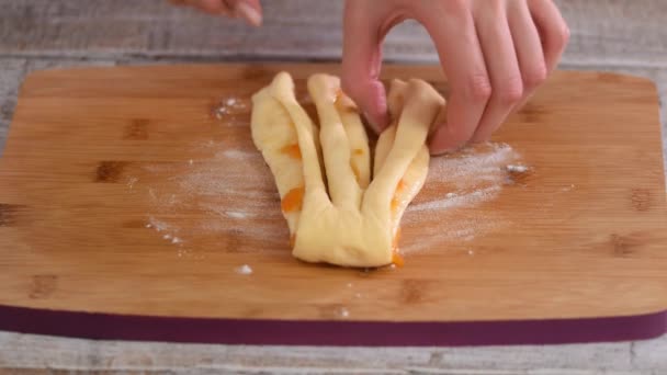 Des mains féminines tressant une pâte. Faire des petits pains à la levure avec confiture d'abricot. — Video