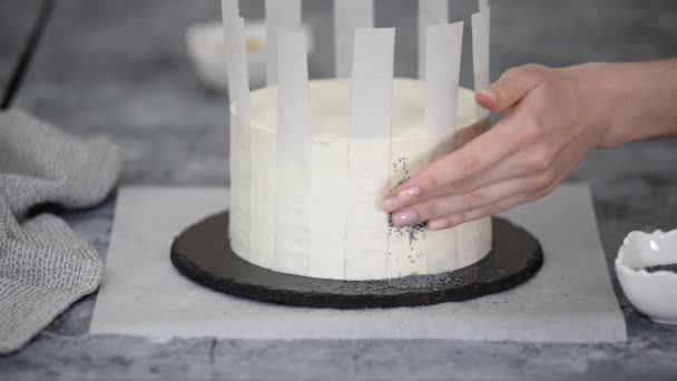 Onherkenbare vrouw gebak chef-kok versiert taart met maanzaad. — Stockvideo