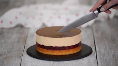 Kadın ev yapımı vişneli pastayı karamel kremalı ve süngerli kek katmanıyla kesiyor..