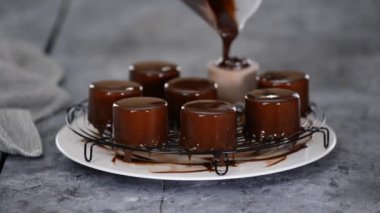 Pasta şefi çikolatalı mus keklerinin üzerine ayna jölesi döker..