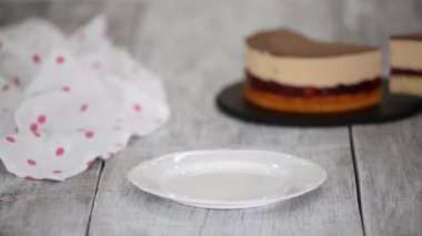 Kadın fırıncı beyaz bir tabağa karamelli kremalı vişneli kek koyuyor..