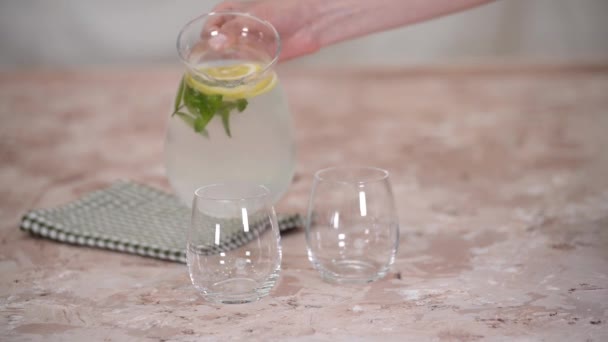 Primer plano de la mujer en la cocina en casa verter limonada en vasos. — Vídeo de stock