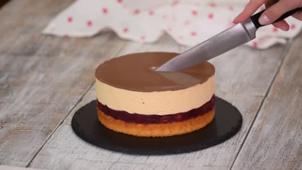 Mujer corta un pedazo de pastel de cereza casero con mousse de caramelo y capa de pastel de esponja. — Vídeo de stock