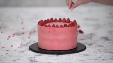 Kadın elleri taze pişmiş pastaya ahududu koyuyor..