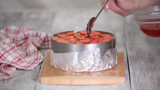 El cocinero vierte la torta de fresa de capa superior con gelatina. — Vídeos de Stock