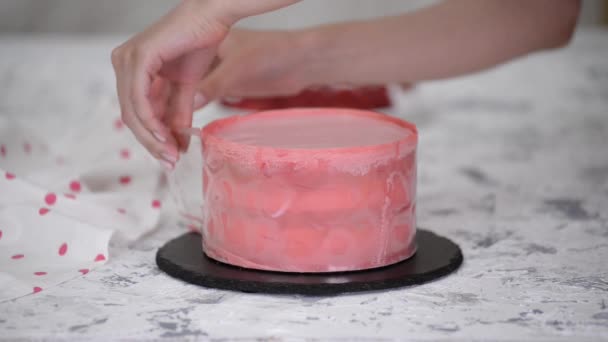 La pastelera femenina decora un pastel de mousse de frambuesa con chocolate rosa. — Vídeo de stock