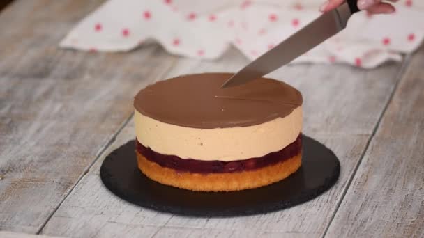 Mujer corta un pedazo de pastel de cereza casero con mousse de caramelo y capa de pastel de esponja. — Vídeo de stock