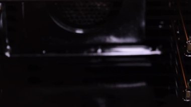 Profesyonel fırıncı elinde çöreklerle bir tepsi tutuyor ve onları elektrikli fırına koymak için hazırlıyor..