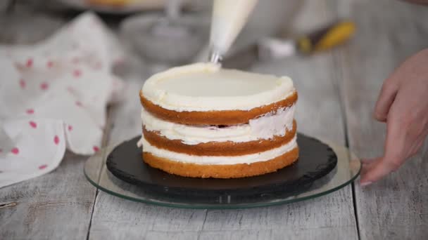 台所でケーキの上にクリームを絞るペストリーバッグと菓子。自家製のペストリー、ケーキの調理の概念. — ストック動画