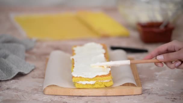 白いクリームとアプリコットジャムと甘いスポンジケーキを作る女性の手のクローズアップ. — ストック動画