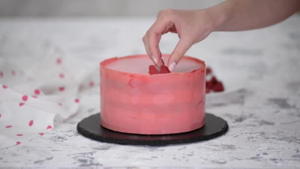 Femme mains plaçant une framboise sur gâteau fraîchement cuit. — Video