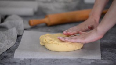 Bir fırıncı, hamuru kağıt tabaklarının arasına yuvarlıyor..