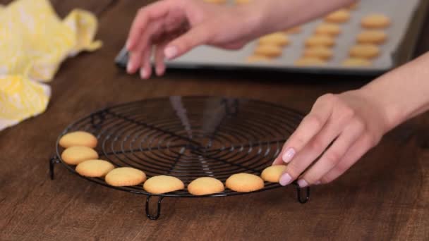 cukrářská kuchařka dává malé vanilkové sušenky na chladící stojan.