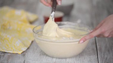 Ev hanımı krep için hamur işi hazırlar. Kadınların elleri hamuru karıştırmak için spatula kullanır..