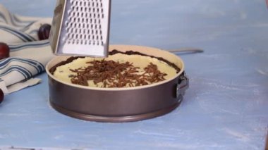 Kadın şef metal rendeleyici tutuyor ve çikolata hamuru rendeliyor. Çikolatalı pasta yapıyorum..