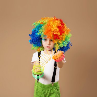 Little boy in clown wig playing with a spring.