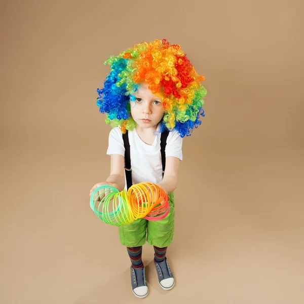 Gelukkig clown jongen met grote kleurrijke pruik. — Stockfoto