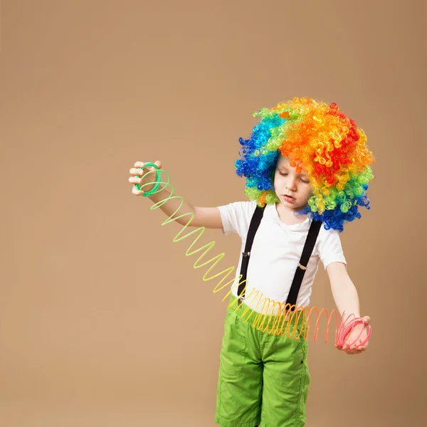 Menino em peruca de palhaço sorrindo e brincando com Magic Spring — Fotografia de Stock