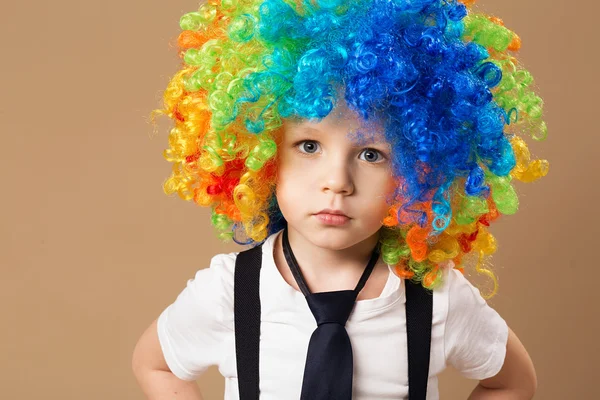 Fröhlicher Clownsjunge mit großer bunter Perücke. — Stockfoto