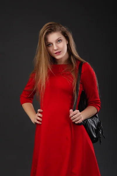 Retrato de una niña en un vestido rojo con una mochila de cuero negro —  Fotos de Stock