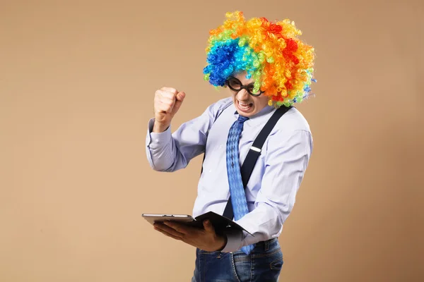 Portret van zakenman in clown pruik met behulp van een tablet aan toegang t — Stockfoto