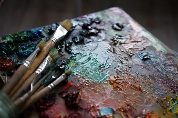 Artists brushes and oil paints on wooden palette — Stock Photo, Image