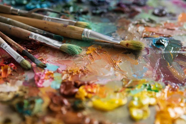 Artists brushes and oil paints on wooden palette — Stock Photo, Image