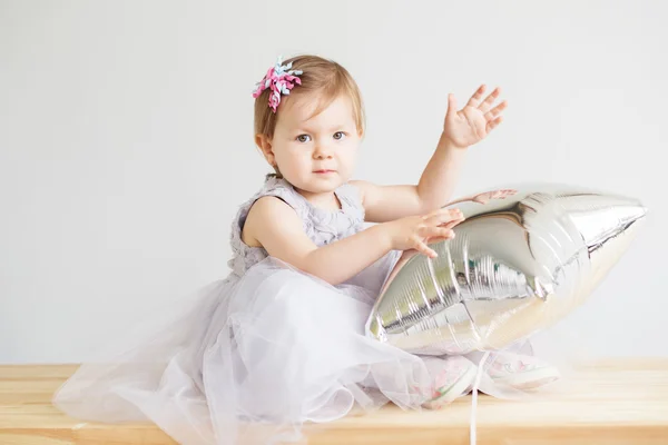 Kleines Mädchen mit silbernem sternförmigen Ballon. — Stockfoto