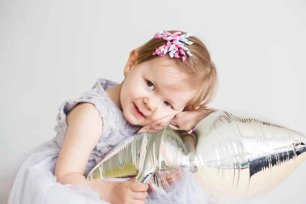 Kleines Mädchen spielt mit silbernem sternförmigen Ballon. — Stockfoto