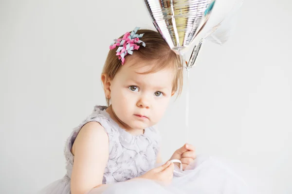 Retrato de una encantadora niña sosteniendo una bola plateada en forma de estrella —  Fotos de Stock