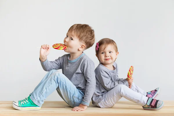 Niños pequeños comiendo piruletas — Foto de Stock