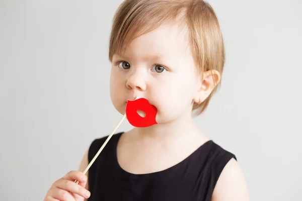 Retrato de uma linda menina com lábios de papel vermelho contra um w — Fotografia de Stock