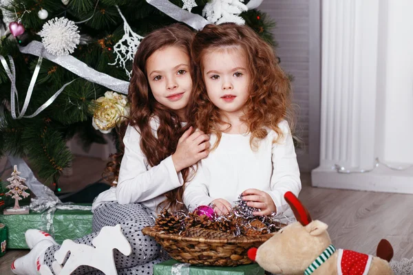 Kleine meisjes in comfortabele huis kleding, zittend op de vloer in bea Stockfoto