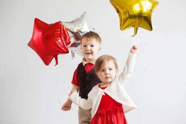 Crianças felizes com balões de folha brilhante coloridos contra um branco — Fotografia de Stock