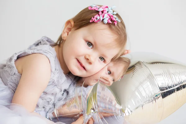 Baby flicka som leker med silver stjärnformade ballong. — Stockfoto