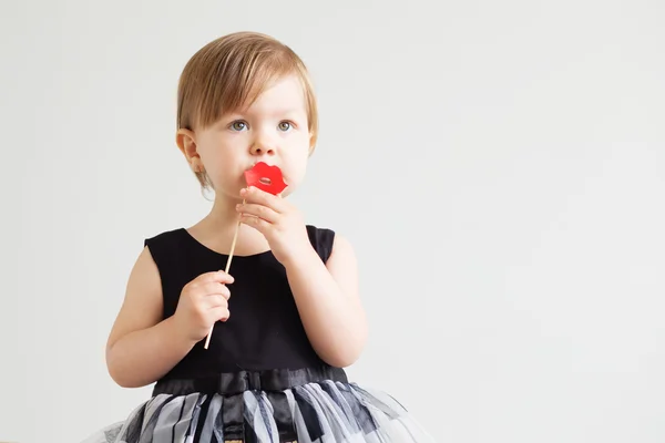 Porträt eines hübschen kleinen Mädchens mit lustigen Papierlippen gegen einen — Stockfoto