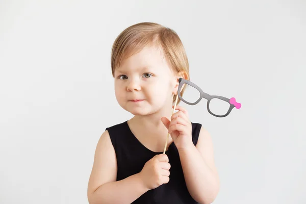 Portrait of a lovely little girl with paper glasses against a wh — Stock Photo, Image