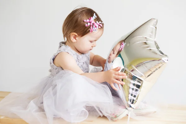 Liebliches kleines Mädchen spielt mit silbernem sternförmigen Ballon. — Stockfoto