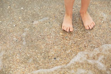 Ayak çocuk kabukları ile kumlu bir plaj üzerinde
