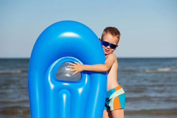 Мальчик-кузнец играет на пляже с воздушной матрешкой — стоковое фото