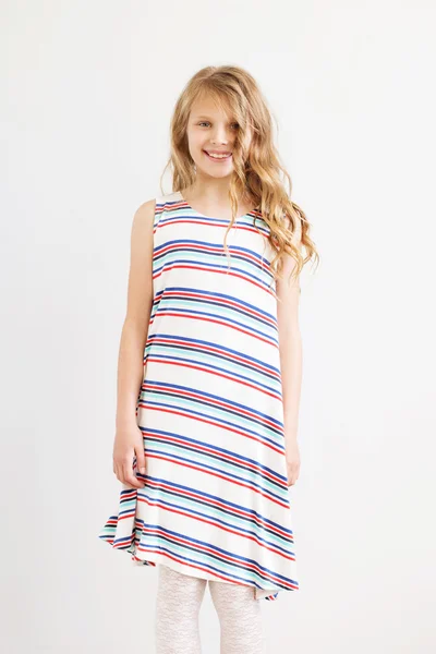 Lovely little girl in a striped dress against a white background — Stock Photo, Image