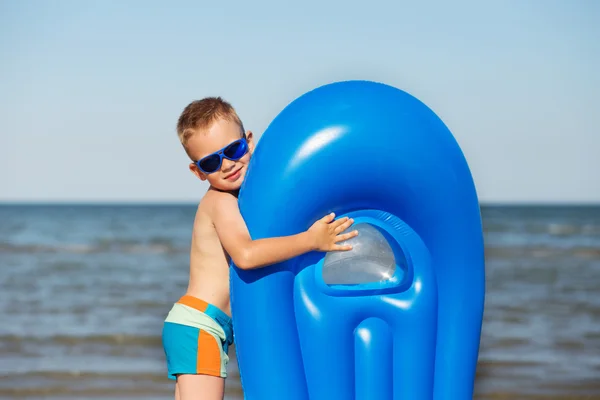Μικρό παιδί κρατώντας ένα φουσκωτό στρώμα στην παραλία με καυτό su — Φωτογραφία Αρχείου