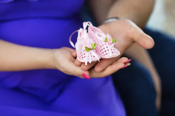 Schwangere Frau und ihr Mann mit Babyschuhen an den Händen — Stockfoto