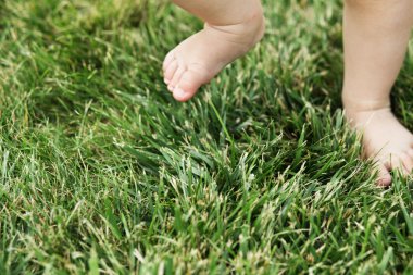 Çimenlerin üzerinde çıplak ayakla ayakta bebek