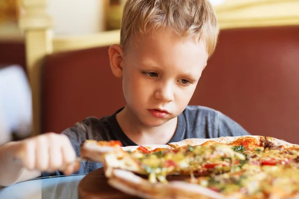 Очаровательный мальчик ест пиццу в ресторане — стоковое фото