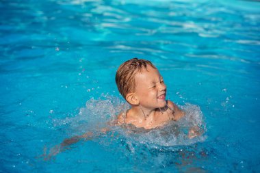 Yüzme Havuzu mavi suda oynayan mutlu çocuk.